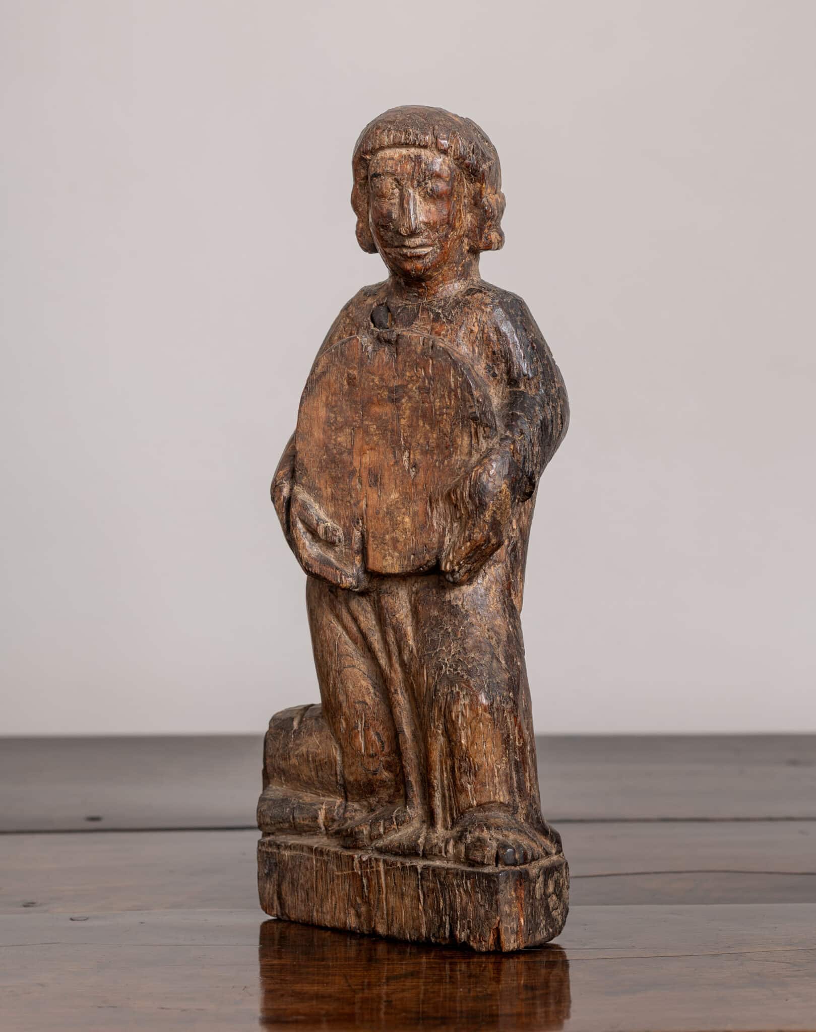 A Late Medieval Carved Oak Figure Holding a Roundel